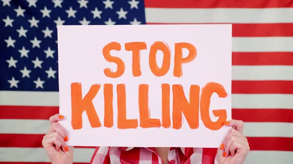 Protester Holds a Banner with a Slogan - Stop Killing - Against Background of the USA Flag. Fighting alt