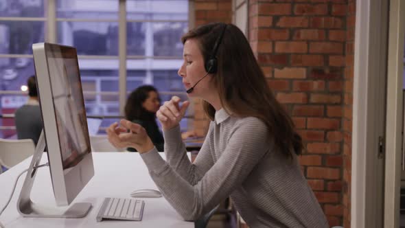 Creative businesswoman wearing headset talking in modern office alt