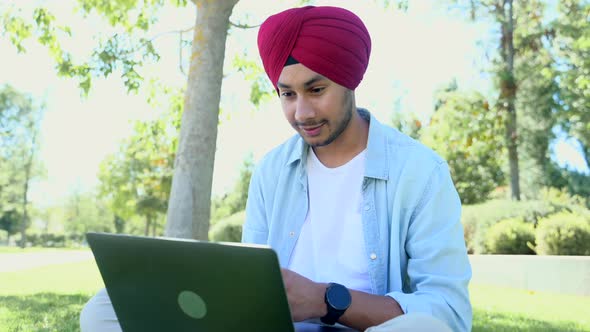 Smiling and Friendly Hindu Male Freelancer Wearing National Headwrap Using Laptop for Video Meeting