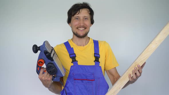 A Man Professional Tile Installer a Wooden Plank and an Electric Planer in His Hands alt