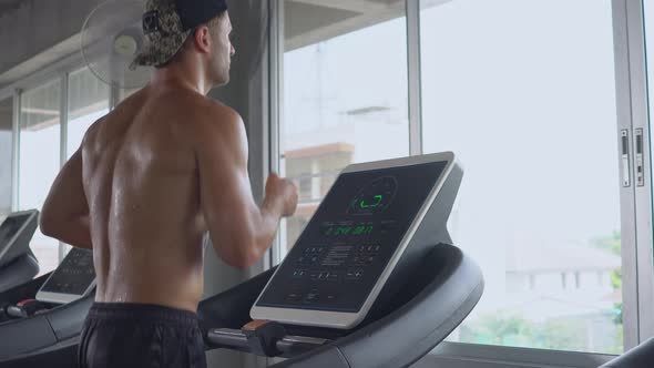 Athletic man running on treadmill in fitness