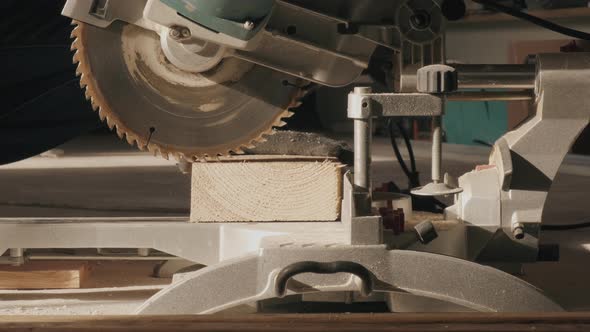 A Construction Worker Cuts a Thick Board with an Electronic Saw