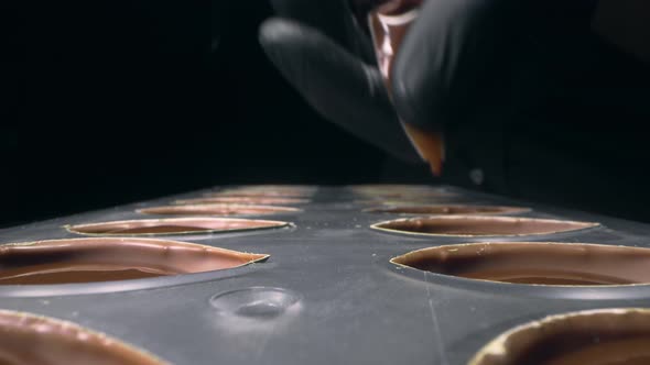 Chocolatier Fills Chocolate Molds with Liquid Chocolate Filling for Praline Sweets , Making of alt