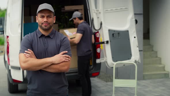 Video portrait of delivery man standing next to moving van. Shot with RED helium camera in 8K. alt