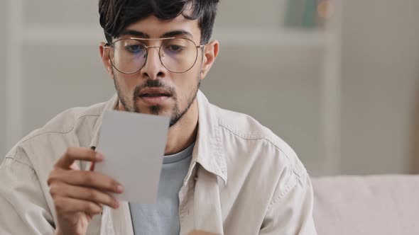 Closeup Arabic Man Bearded Guy with Glasses Sitting at Home Indoors Receives Envelope with Bad News alt