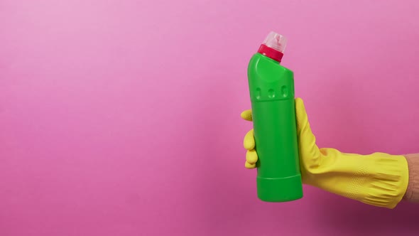 Green Bottle with Household Chemicals and a Hand in Rubber Protective Gloves