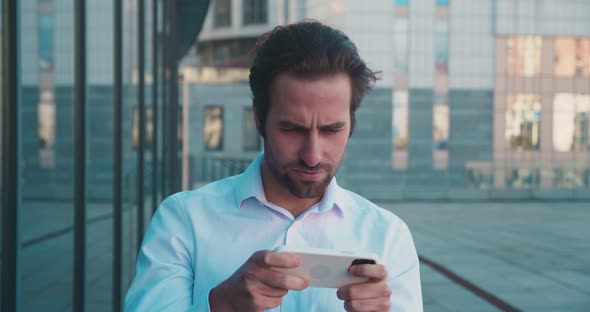 Expressive Stylish Mature Businessman Playing Mobile Game alt