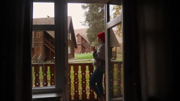 Woman in a Knitted Red Hat and Scarf Drinks Hot Tea Standing alt
