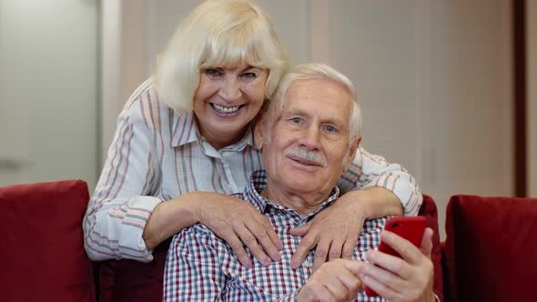 Senior Grandparents Couple Talking and Using Digital Mobile Phone at Home. Coronavirus Lockdown alt