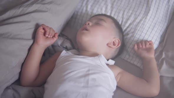 Relaxing video clip of a lovely two years old Asian toddler comfortably and deeply sleeping or takin alt