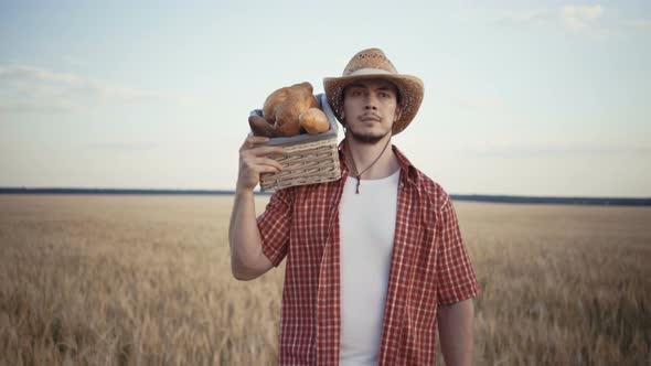 Young Farmer Are Walking Along the Wheat Field with Bread Baskets alt