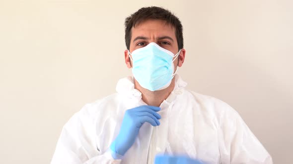 Doctor in PPE suit putting on hood while looking at camera, Stock Footage