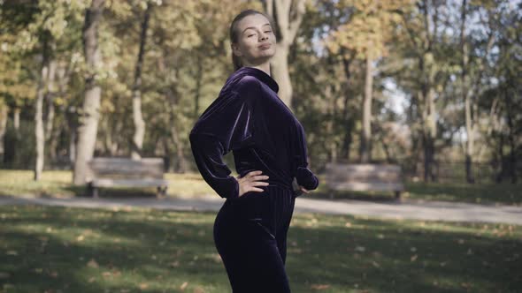 Side View of Slim Confident Caucasian Sportswoman Posing in Sunlight and Smiling alt