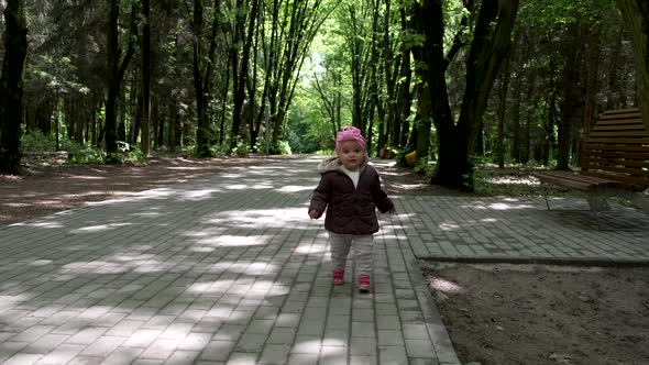 A little girl runs in the park, slow-motion. alt