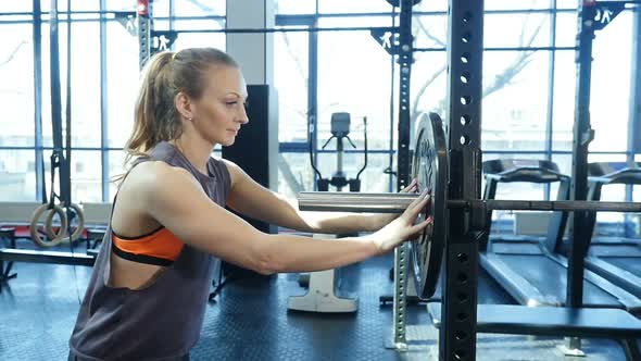 Young Fitness Woman Getting Ready for Weights Lifting Exercise. Sports Woman Training in Gym.