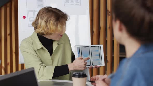 Female App Developer Showing Interface Ideas to Colleagues alt