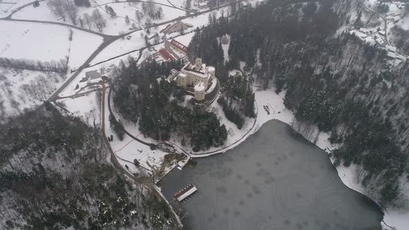 Aerial view of frozen lake and fairy tale castle in the distance at winter alt