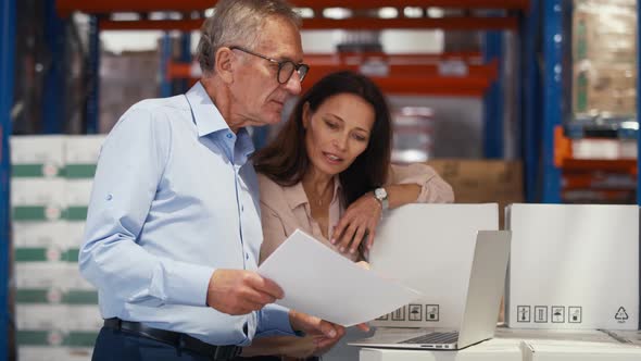 Mature woman and man working togetherness in the warehouse. Shot with RED helium camera in 8K. alt
