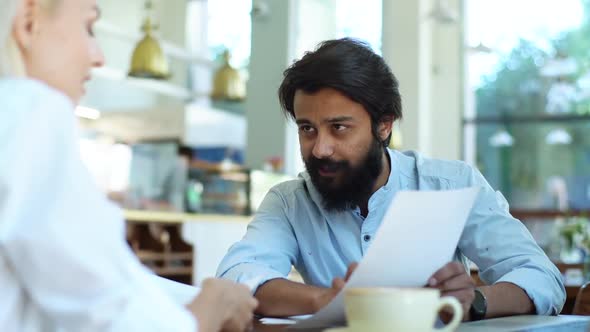Closeup Side View of Two Happy Colleagues Discuss Financial Data in Report Using Paper Documents alt
