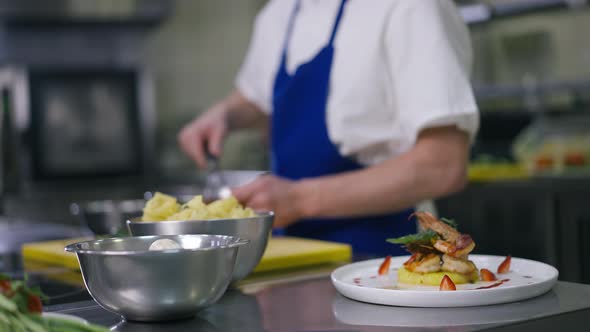 Cooked Seafood and Raw Ingredients in Commercial Kitchen with Unrecognizable Male Cook Mixing in alt