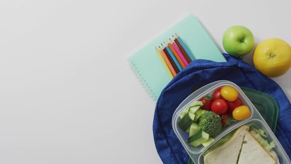 Video of healthy packed lunch of fruit and vegetables, with coloured pencils on schoolbag alt