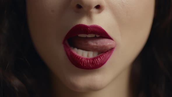 Close Up of Unrecognizable Girl Face Licking Red Plump Lip with Tongue alt