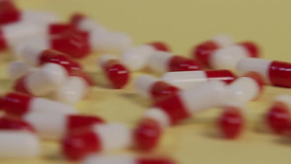 Slow motion close-up of a single pill as several pills roll by and push it out of frame. alt