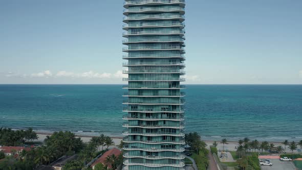 Drone Flying Around Tower Building with Scenic Sandy Beach and Blue Ocean View alt