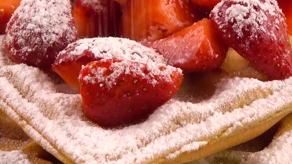 Belgian waffles with strawberry and powdered sugar on a stone board on an orange background alt