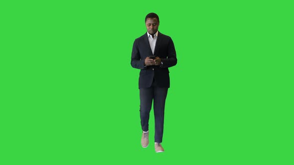 Confident Black Entrepreneur Walking and Using a Mobile Phone on a Green Screen Chroma Key alt
