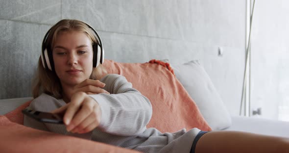 Caucasian woman listening to music in hotel room alt
