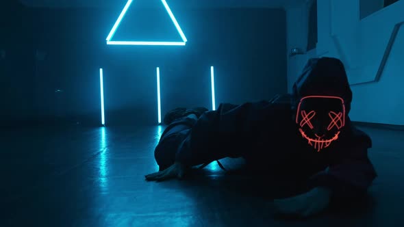 Unknown Person in Neon Mask Enjoying Hip Hop Moves in Dark Studio with Smoke alt