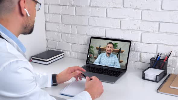 Doctor in Hospital Office Greets Tells Patient Online Video Call Webcam Laptop alt