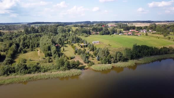 Aerial shot of a secluded lake, surrounded by fields and farms. Relaxing scenery. Beautiful colors. alt