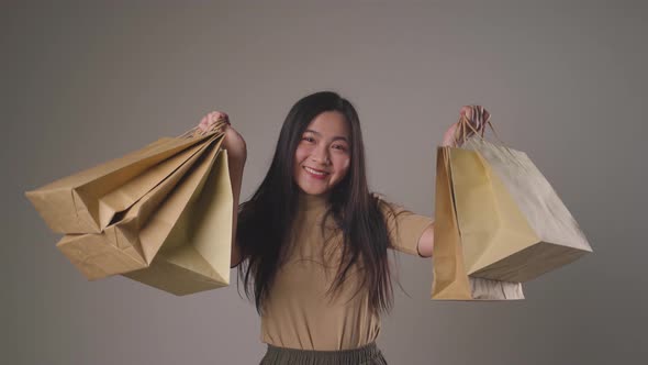 Confident asian woman happy holding shopping bag dancing smilling and looking at camera