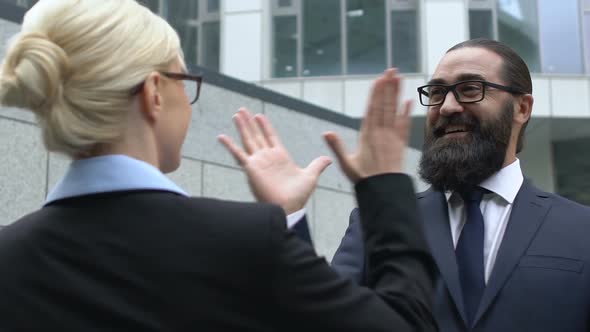 Woman and Man in Formalwear Making High-Five Gesture, Celebrating Success, Deal