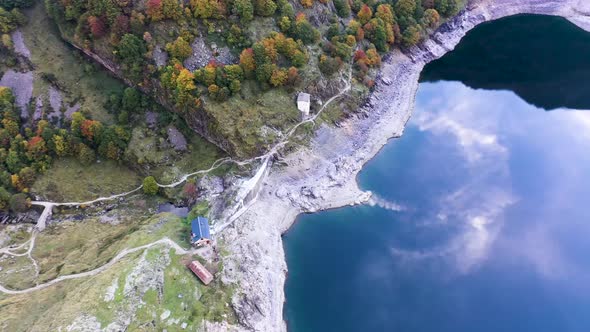 Lac d'Oô dam stone wall and keeper's cabin at artificial lake in the French Pyrenees with water stre alt