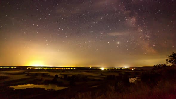 Starry Night in Mountains Time Lapse. Milky Way Galaxy Stars Moving Over Countryside Traffic. Night alt