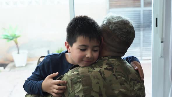 Military soldier man hugging his son at home - Father and child love
