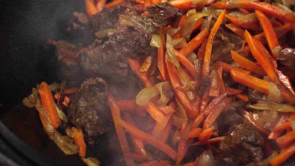 Stirring Stewing Ingredients for Uzbek Pilaf with a Slotted Spoon alt