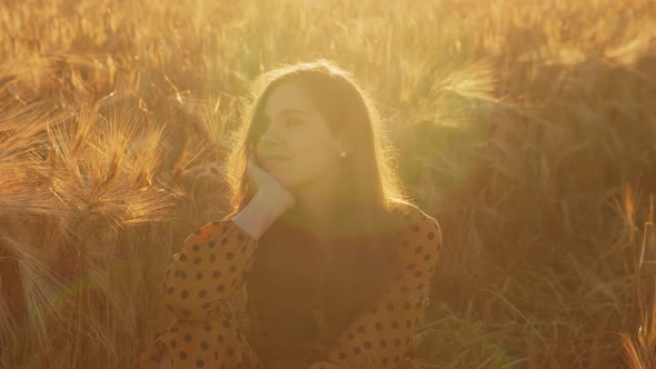 Pregnant woman in the rays of the sunset in the field alt