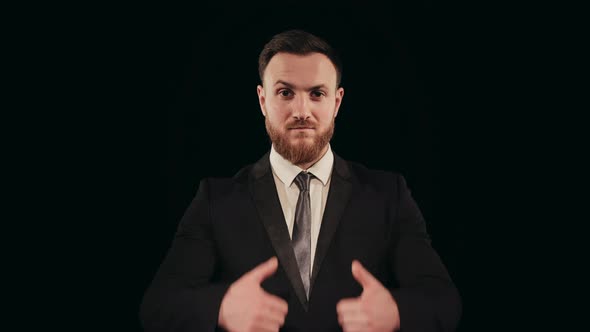 A Man in a Suit is Standing on Stage and Looking at the Camera alt