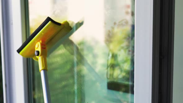 Cleaning the Glass Window of the House Using a Mop Going Up and Down alt