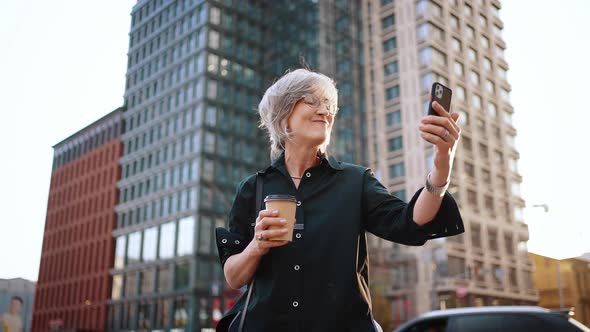 Attractive Businesswoman Talking on Video Communication Using Phone While Standing in the Middle of alt
