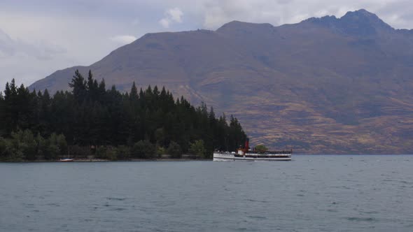 Wide shot of TSS Earnslaw arriving to Queenstown with Cecil's Peak behind. Lake Wakatipu, Queenstown alt
