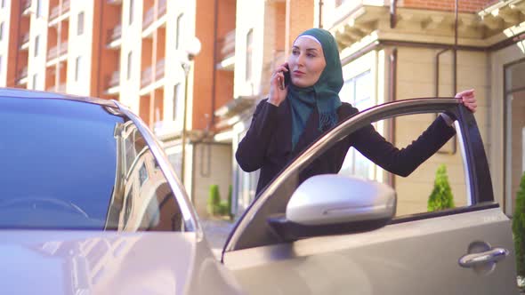 Muslim Woman in Hijab Talking on the Phone and Sits in the Car alt