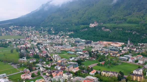 Picturesque View Of Vaduz Town Nestled In The Foothills Of Dense Mountains In Liechtenstein. Aerial alt
