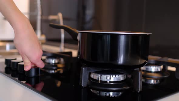 Woman Puts Pot on Gas Stove Turns on Gas to Cook Lunch or Dinner for Whole Family alt