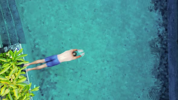 Young Caucasian Man Jumps in Pool with Blue Water alt