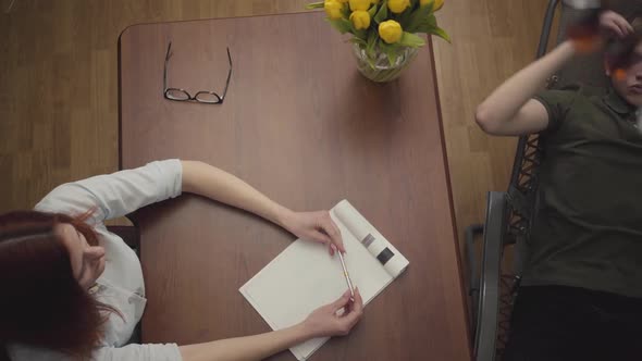 Relaxed Young Man Lying on a Cot in the Office of a Psychologist, Telling Her About His Problems alt